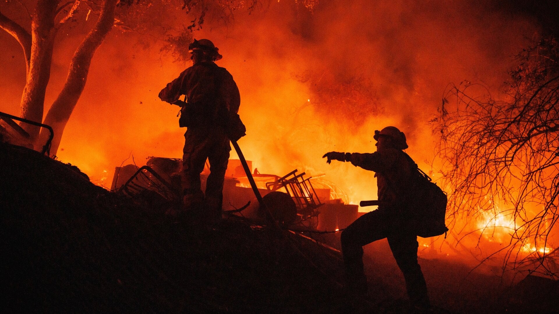 Firefighters coordinate efforts at a burning property while battling the Fairview Fire on Monday, Sept. 5, 2022, near Hemet, California.