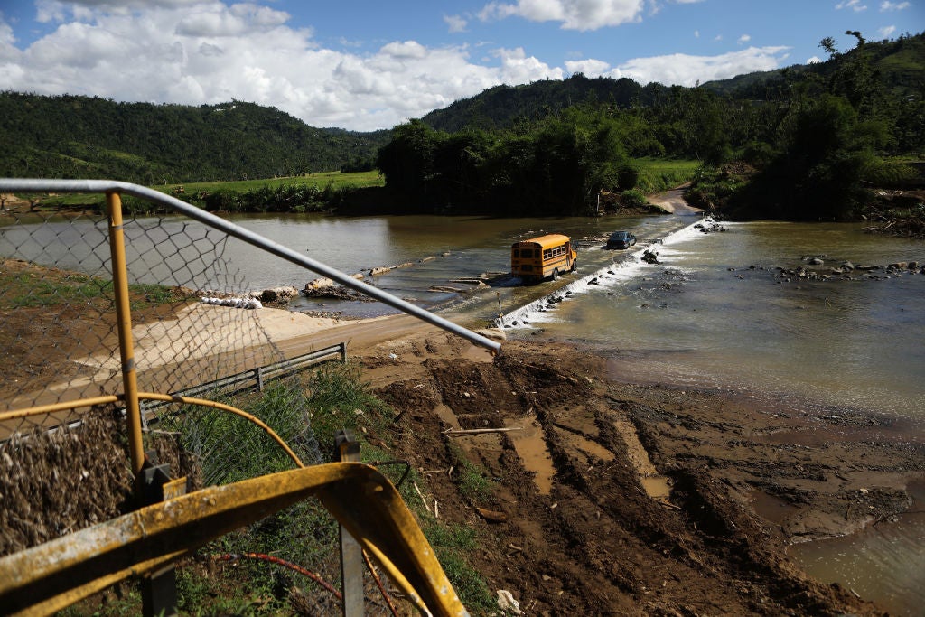 A school bus crosses a makeshift bridge for vehicles, near where the original bridge was washed away by Hurricane Maria flooding, on December 20, 2017 in Morovis, Puerto Rico.