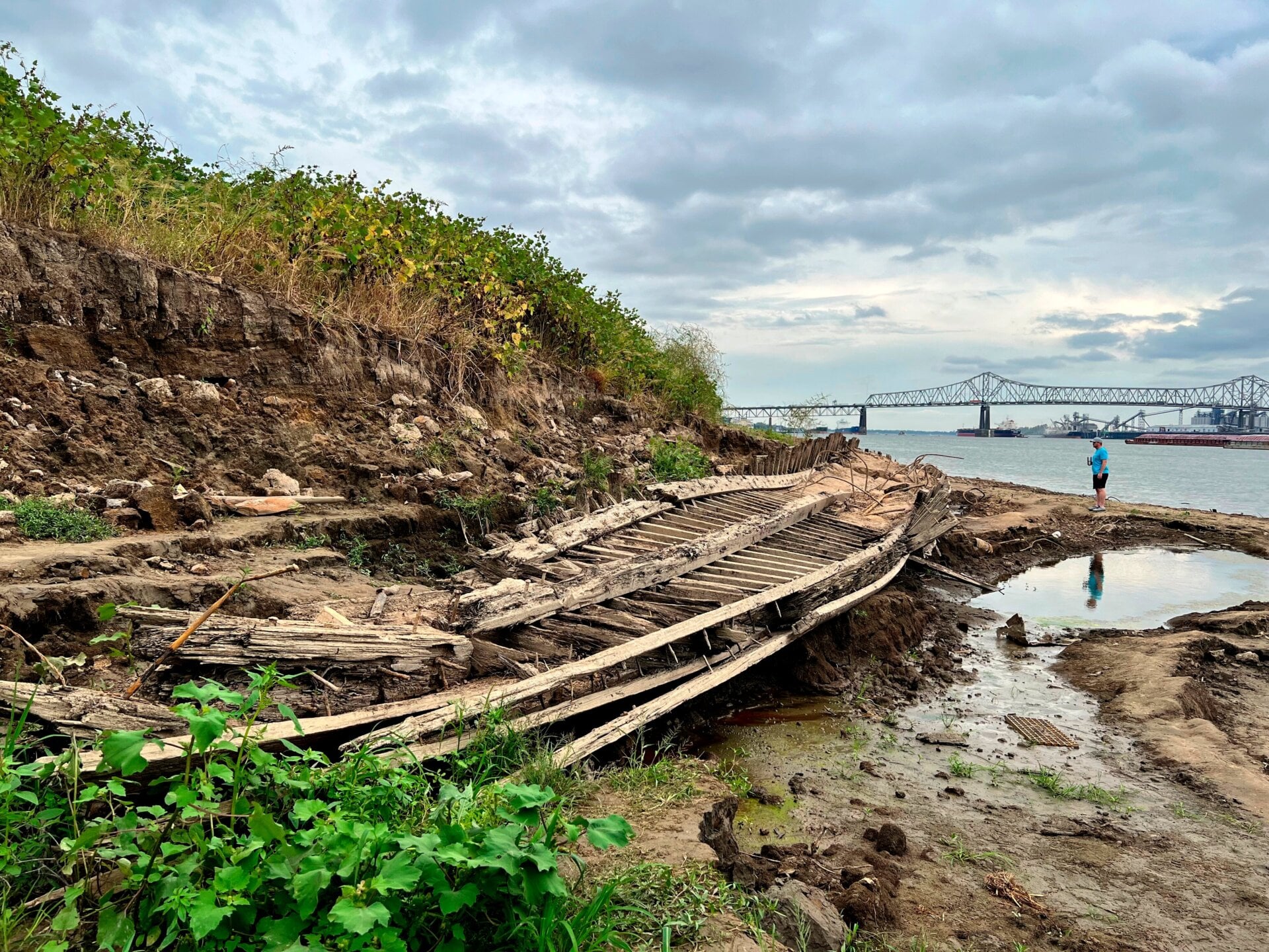A man walking along the Mississippi River in Baton Rouge, La., stops to look at a shipwreck revealed by the low water level, Oct. 17, 2022. Archaeologists believe the ship sunk in the late 1800s to early 1900s.