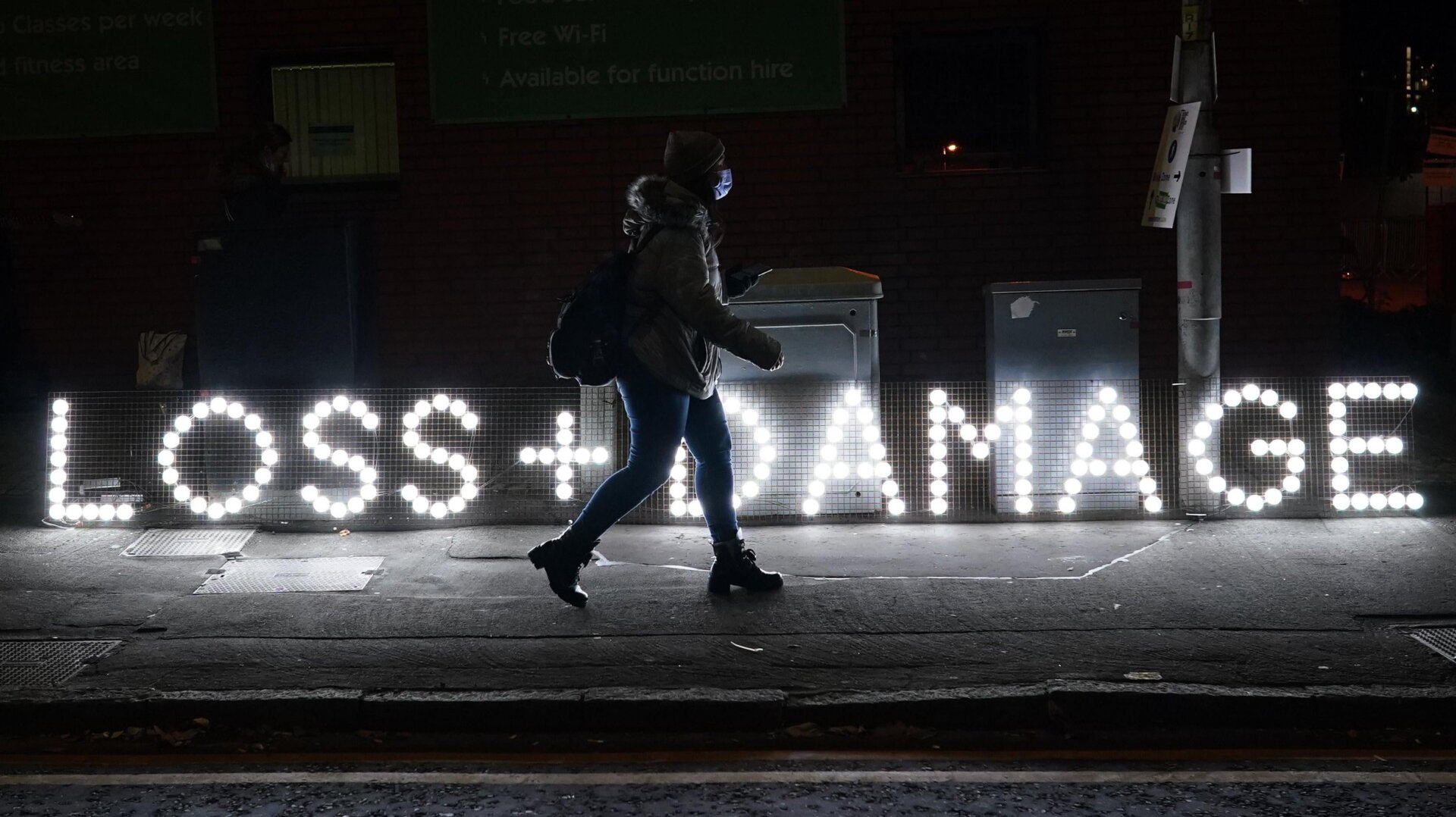 A woman walks by a lit sign in Glasgow on November 4, 2021 at last year’s COP.