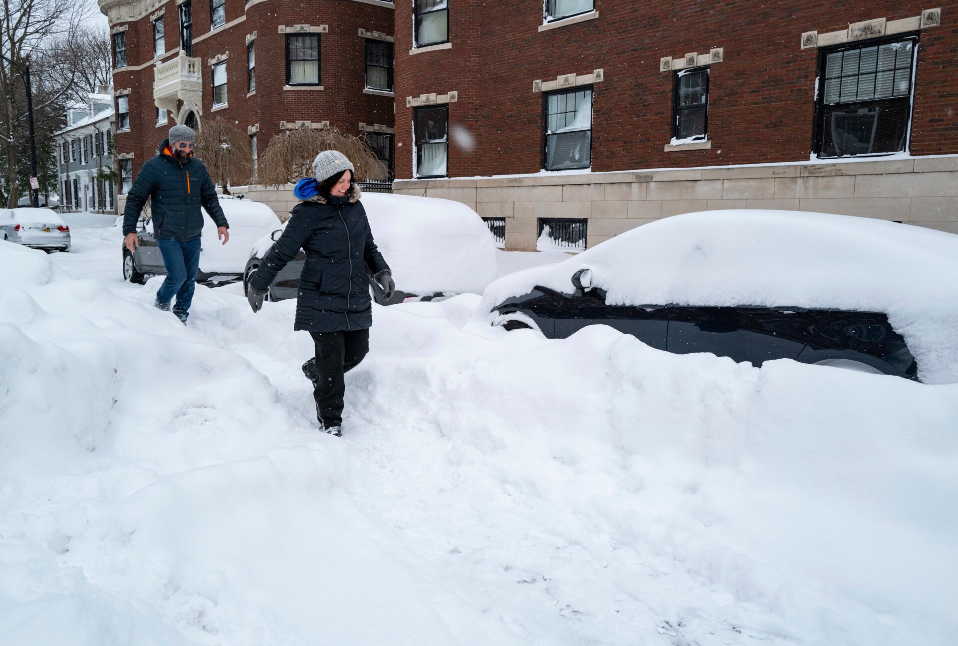 Joseph McVay, left, and Sarah Guglielmi who live nearby, walk along a street in the Elmwood Village neighborhood of Buffalo, N.Y. Monday, Dec. 26, 2022, after a massive snow storm blanketed the city.