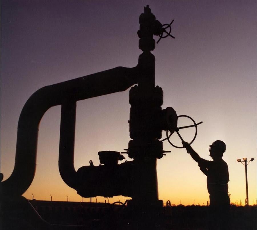 A silhouetted technician works on a wellhead of the Strategic Petroleum Reserve.