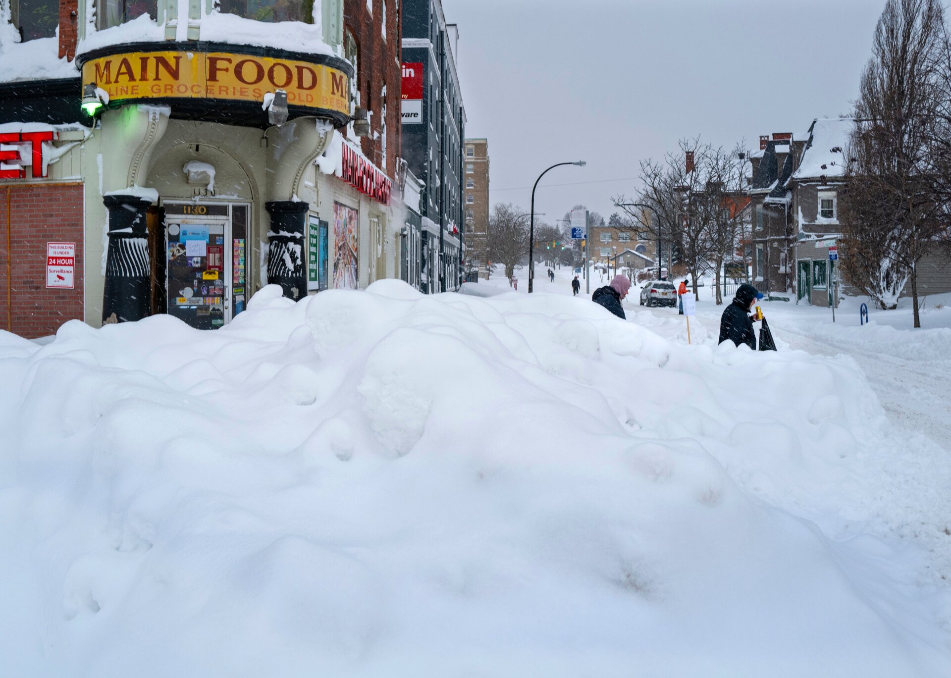 People walk from a grocery store in Buffalo, N.Y. Monday, Dec. 26, 2022, after a massive snow storm blanketed the city. 