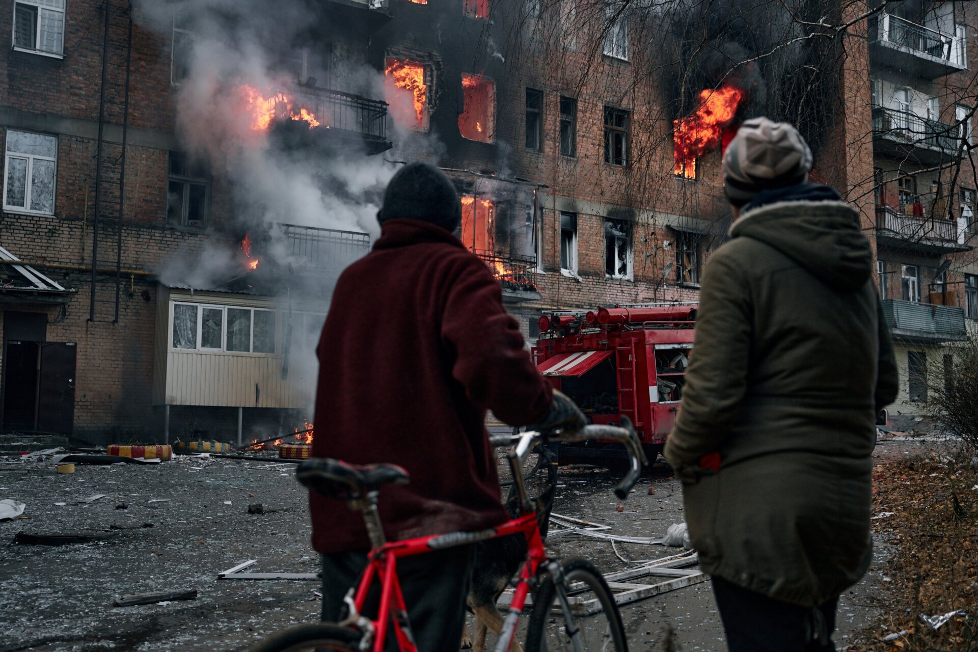 Local residents in Bakhmut, Ukraine look on as a building burns following Russian bombing in early December. 