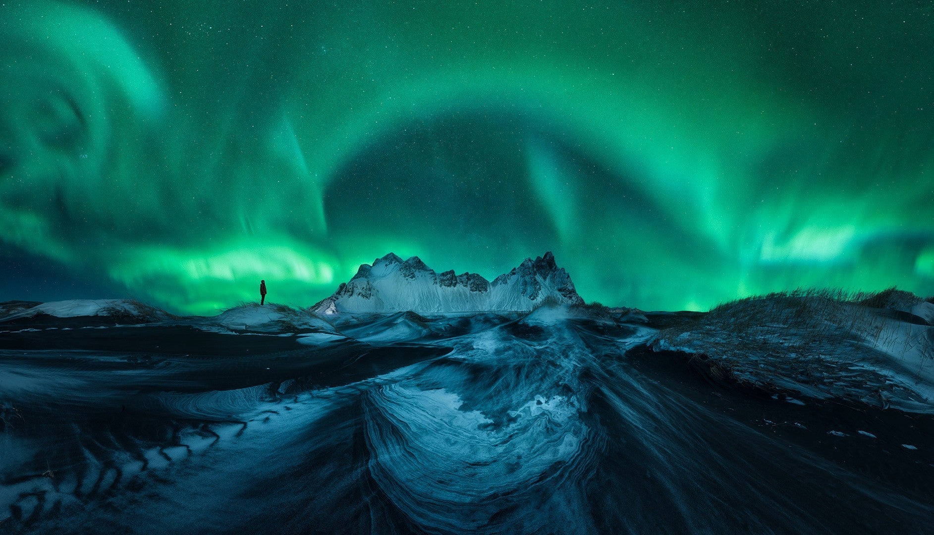 A person silhouetted under the Northern Lights.