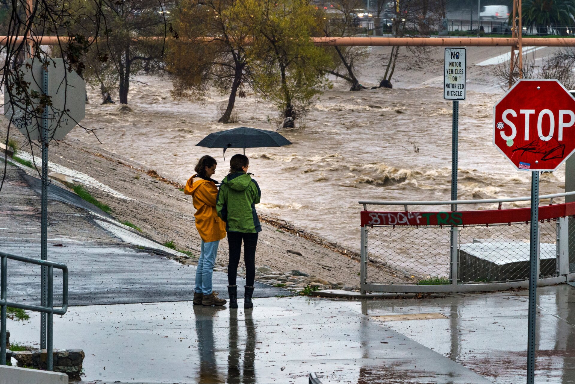 People watch the high volume of storm rain water flowing downstream at the Los Angeles River in Los Angeles on Saturday, January. 14, 2023