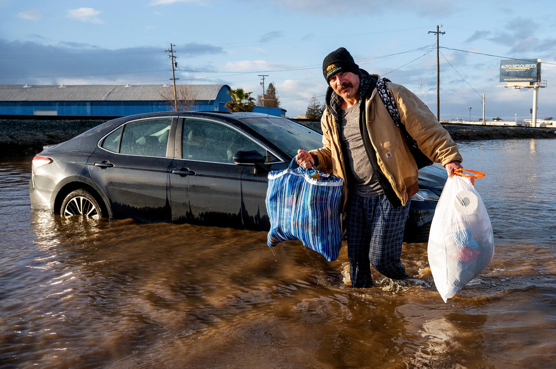  Jesus Torres, whose home in Merced flooded, carries his belongings on Tuesday, January 10.