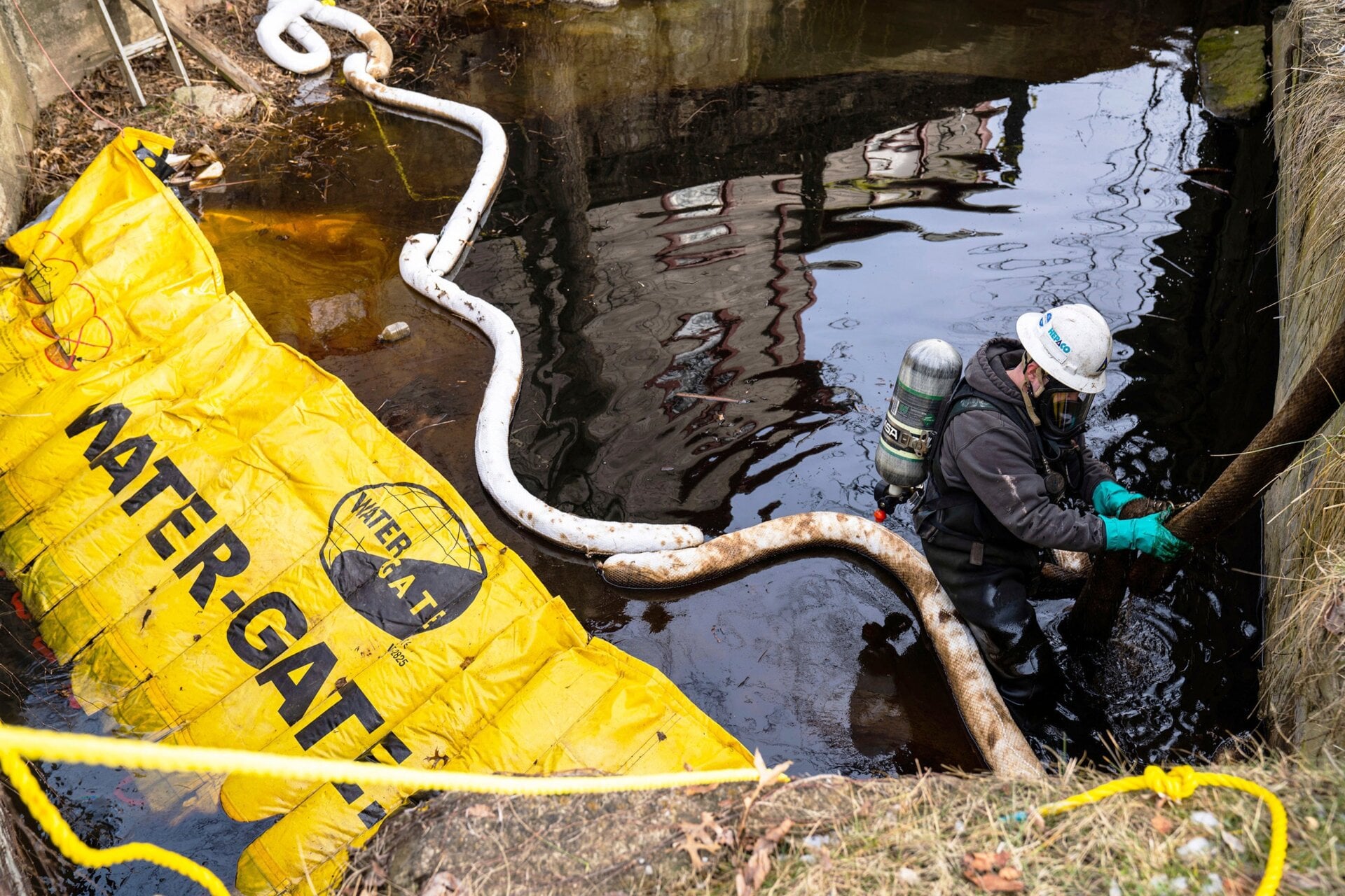 An employee of HEPACO works in a creek along Sumner Street in downtown East Palestine, Ohio, on Sunday, Feb. 5, 2023.