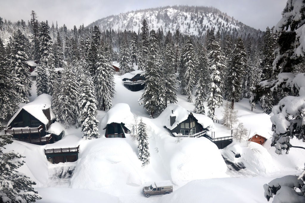 A vehicle navigates a snowy roadway lined with snowbanks piled up from new and past storms in the Sierra Nevada mountains, on March 12, 2023 in Mammoth Lakes, California. 