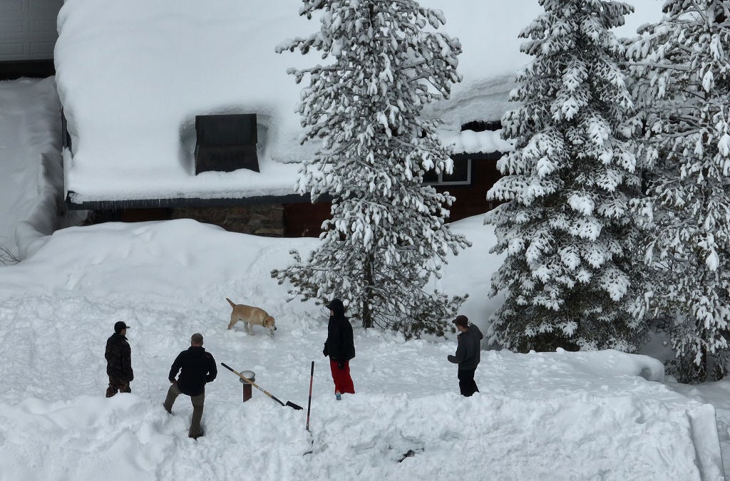Residents stand on the roof of a snow-covered home on March 21, 2023 in South Lake Tahoe, California. 