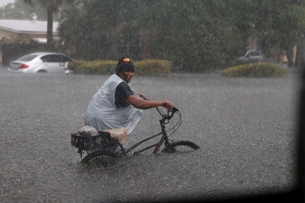  A person walks his bike through a flooded street on April 13, 2023 in Fort Lauderdale, Florida.