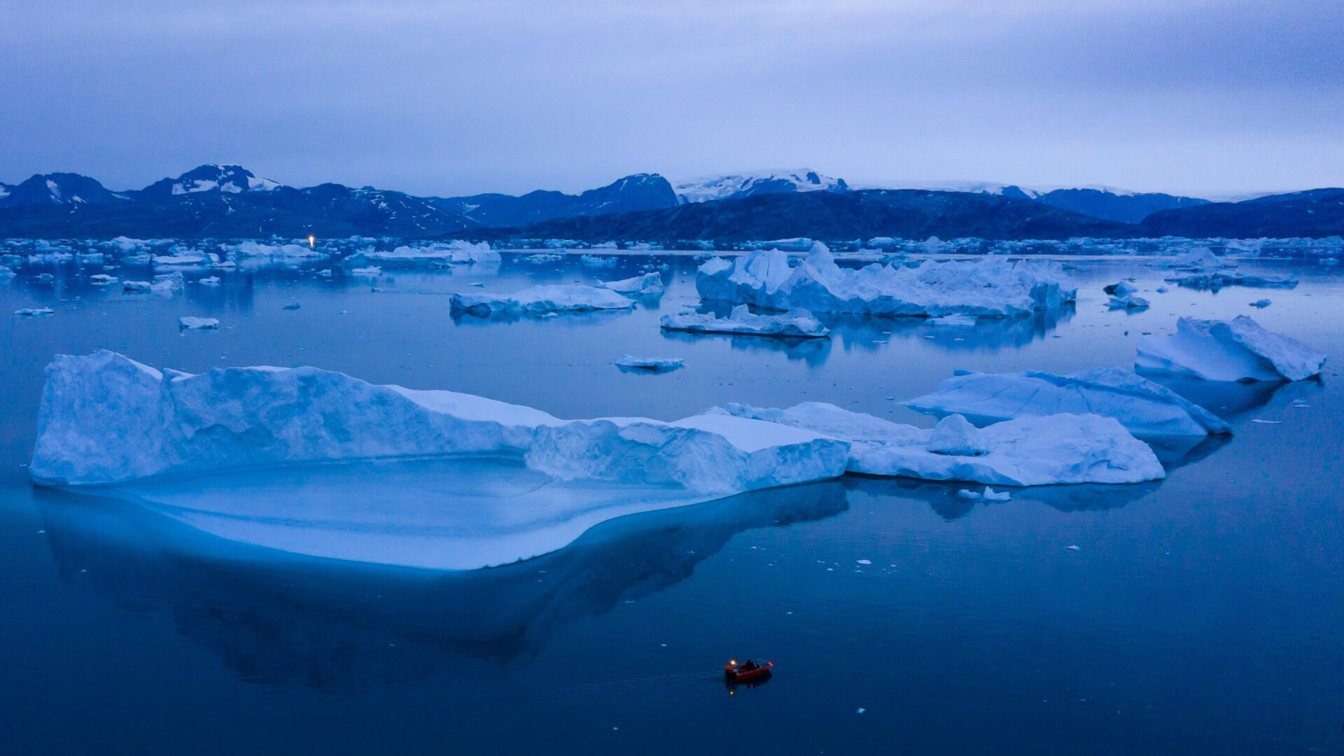 A boat navigates around icebergs in eastern Greenland in 2019.