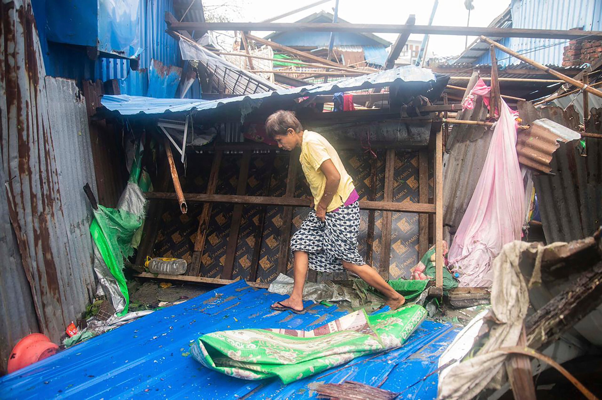 A woman assesses the ruins of homes in Sittwa, the capital of Rakhine, on May 15, 2023.
