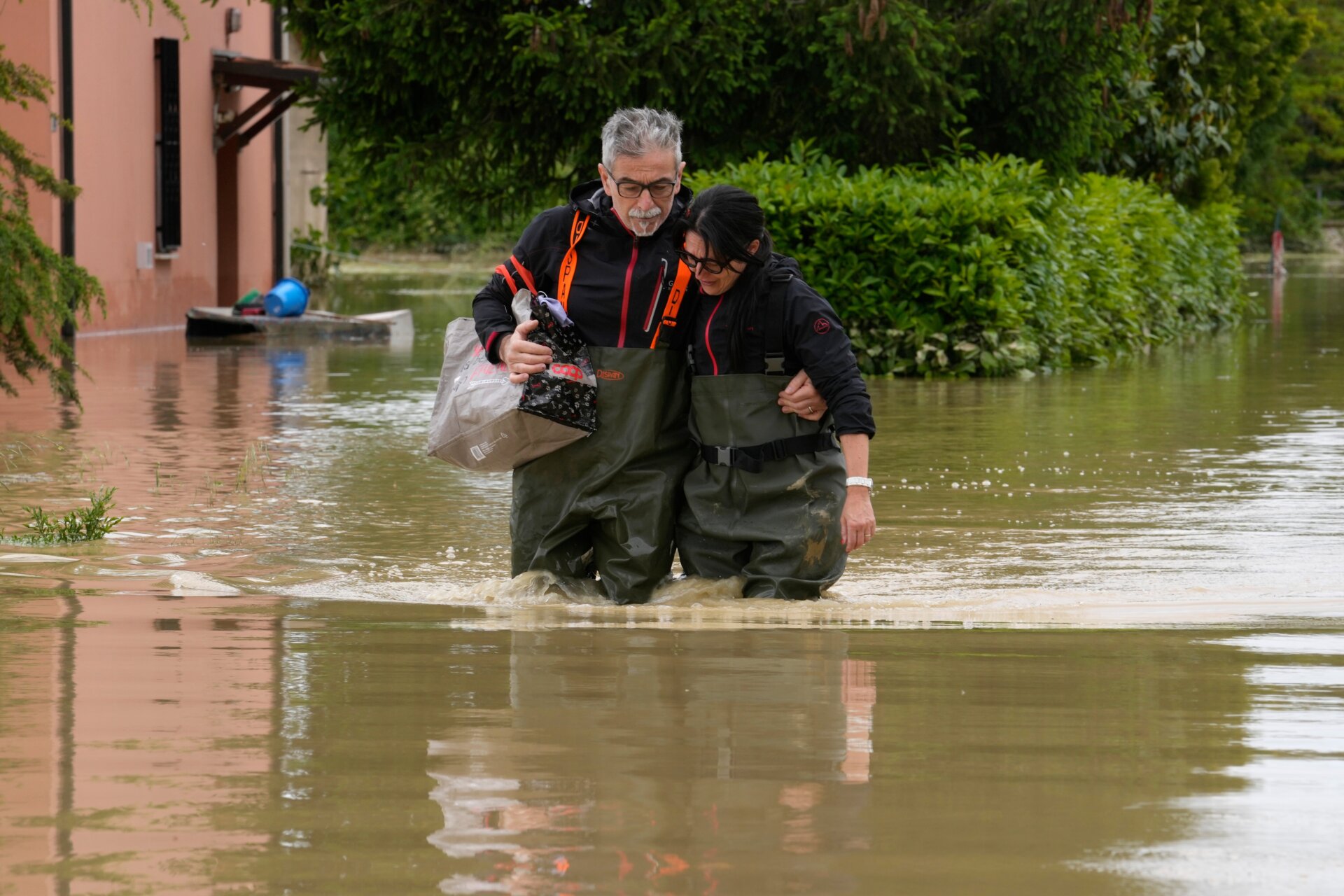Two people lean on each other while wading through feet of murky water in Lugo, Italy on May 18. 