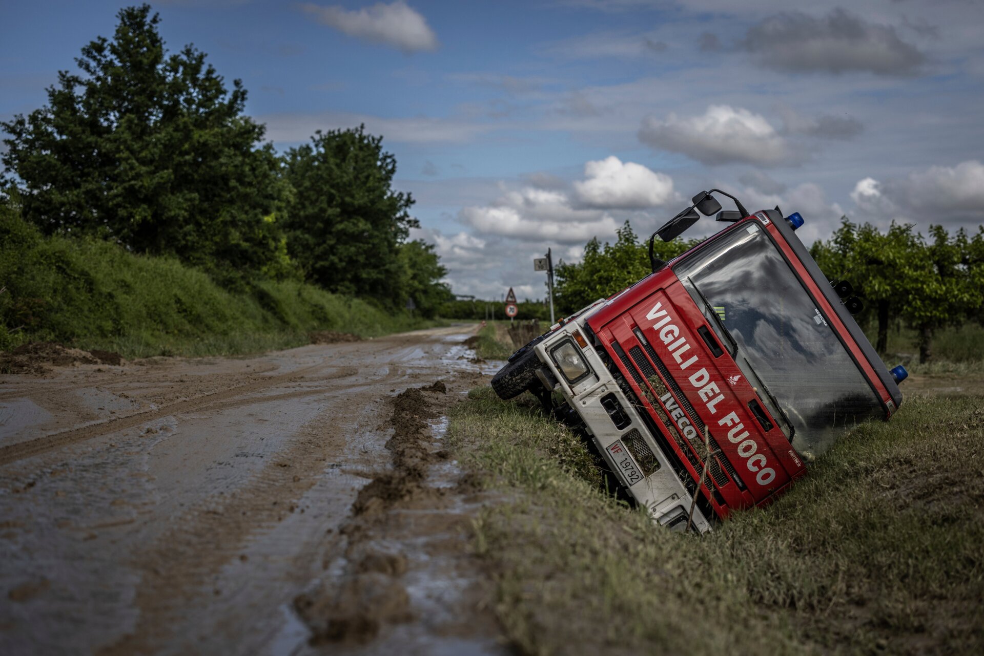 An firetruck lies overturned on its side in a ditch alongside a roadway, following heavy floods in Castel Bolognese, Italy. 