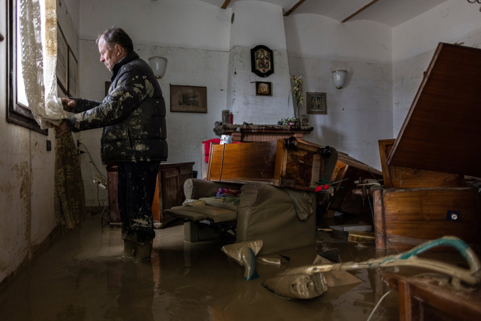 Guiseppe Beltrame stands in his living room in Faenza, Italy, where a water line on the wall shows the height that floodwaters reached.