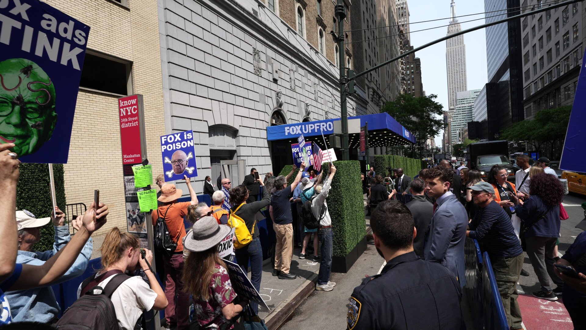Protesters gather in front of Fox News’ latest Upfront conference with large billboard trucks stationed nearby.