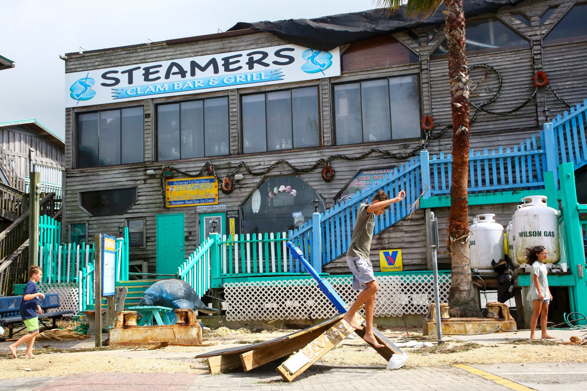 A local climbs on debris outside of Steamers seafood shack and bar after their waterside deck was damaged on August 30, 2023, in Cedar Key, Florida in the wake of Hurricane Idalia. 