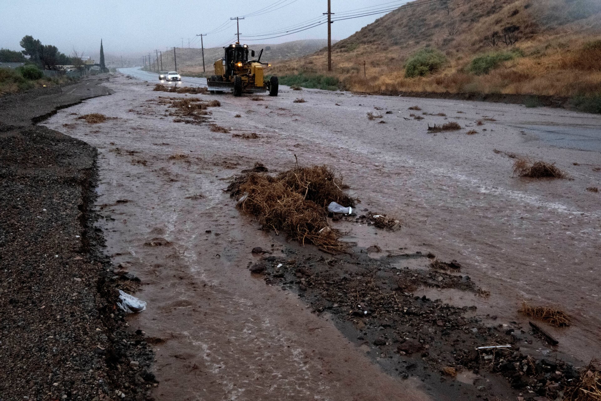 A plow clears debris along a flooded Sierra Highway in Palmdale, California, as Tropical Storm Hilary moves through the area on Sunday, August. 20, 2023.