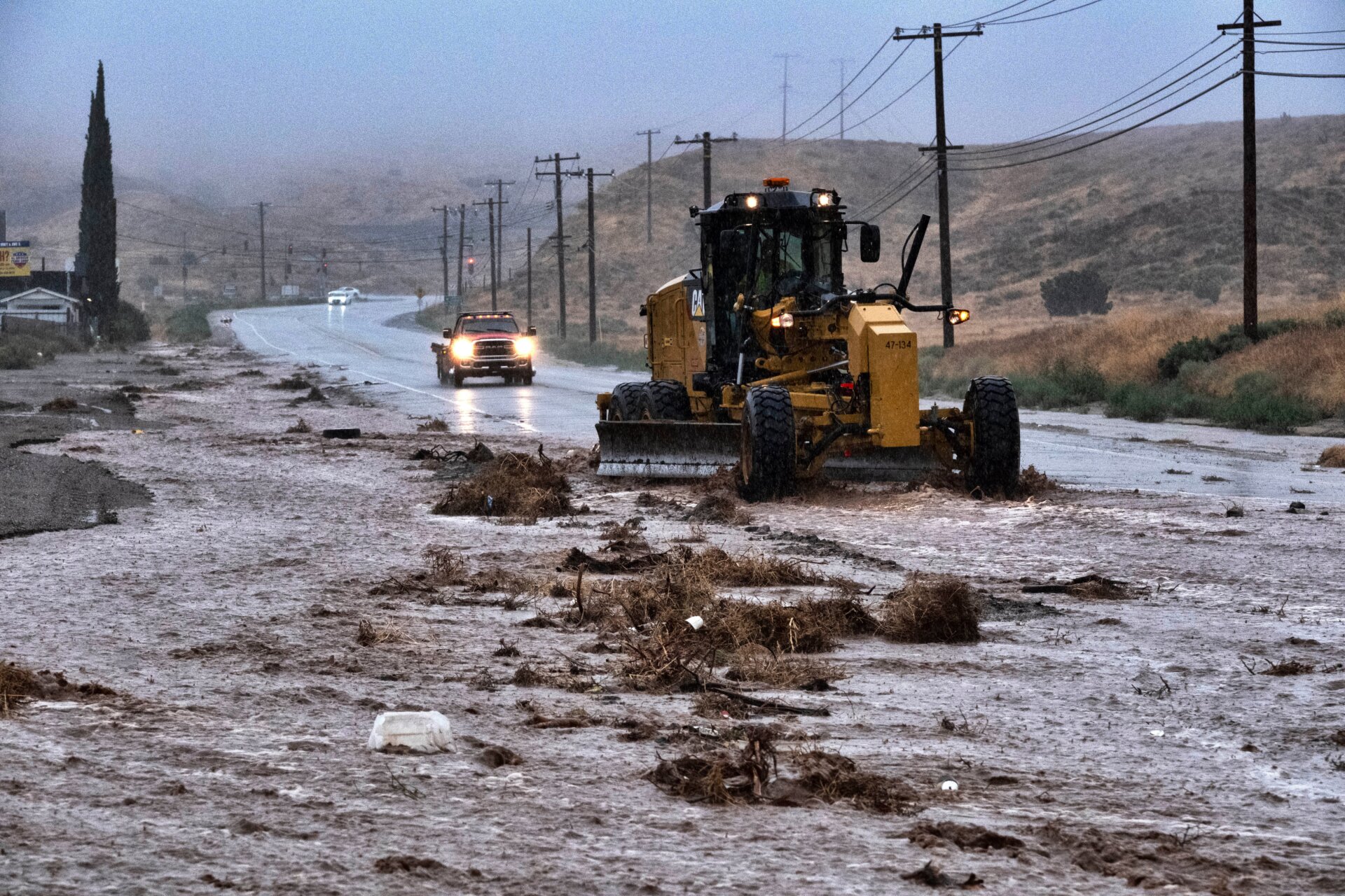 A plow clears debris along a flooded Sierra Highway in Palmdale, Calif., as Tropical Storm Hilary moves through the area on Sunday, August. 20, 2023.