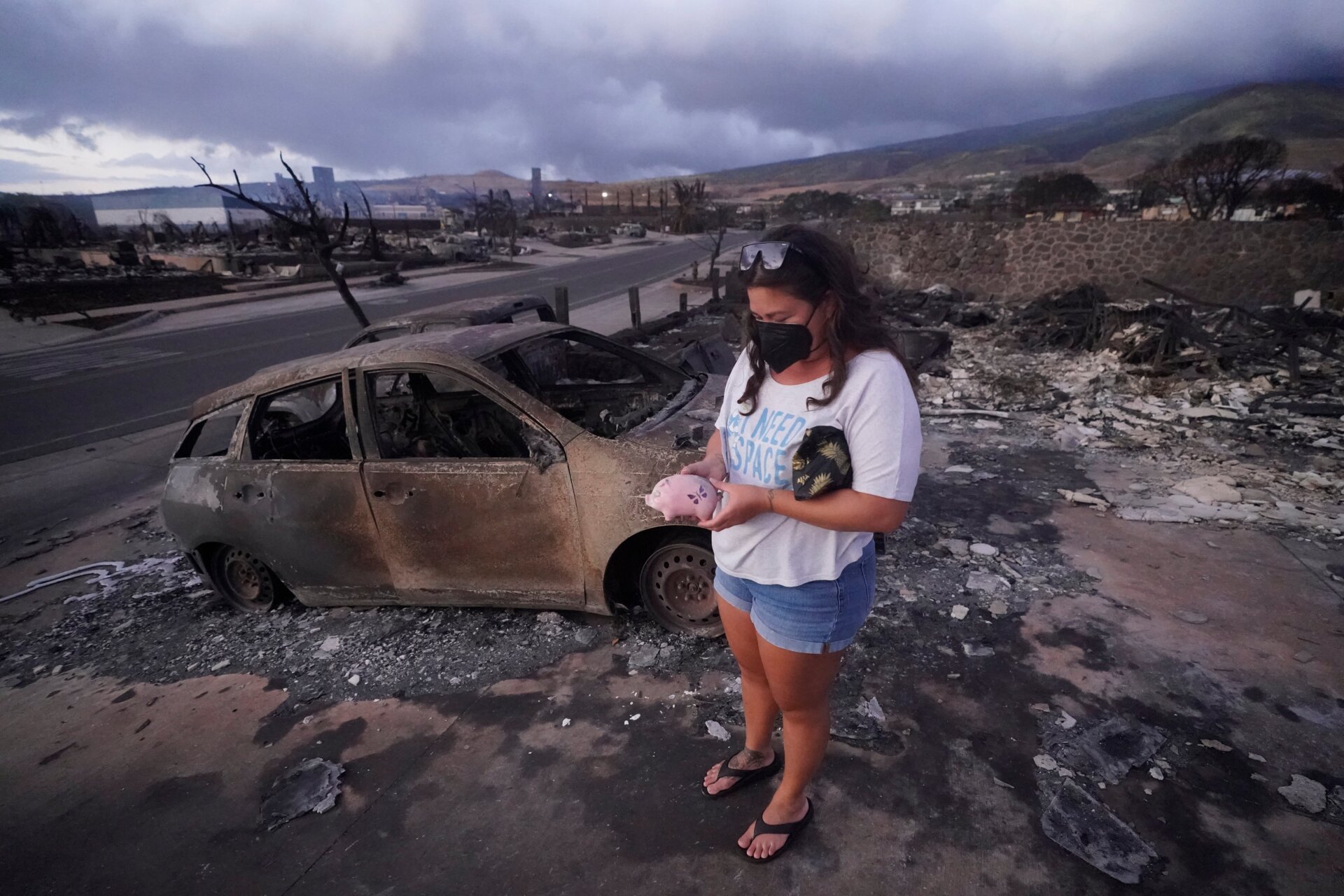 Summer Gerlingpicks up her piggy bank found in the rubble of her home following the wildfire Thursday, August. 10, 2023, in Lahaina, Hawaii.