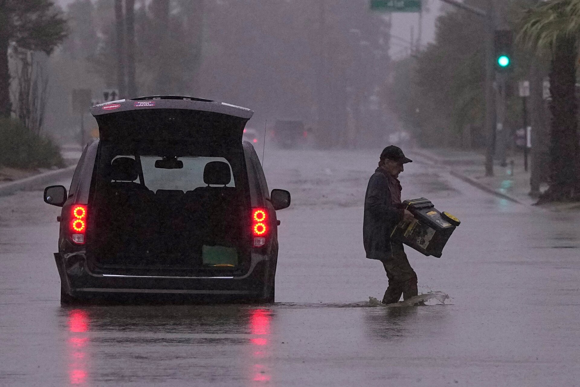 A motorist removes belongings from his vehicle after becoming stuck in a flooded street, Sunday, August. 20, 2023, in Palm Desert, California.
