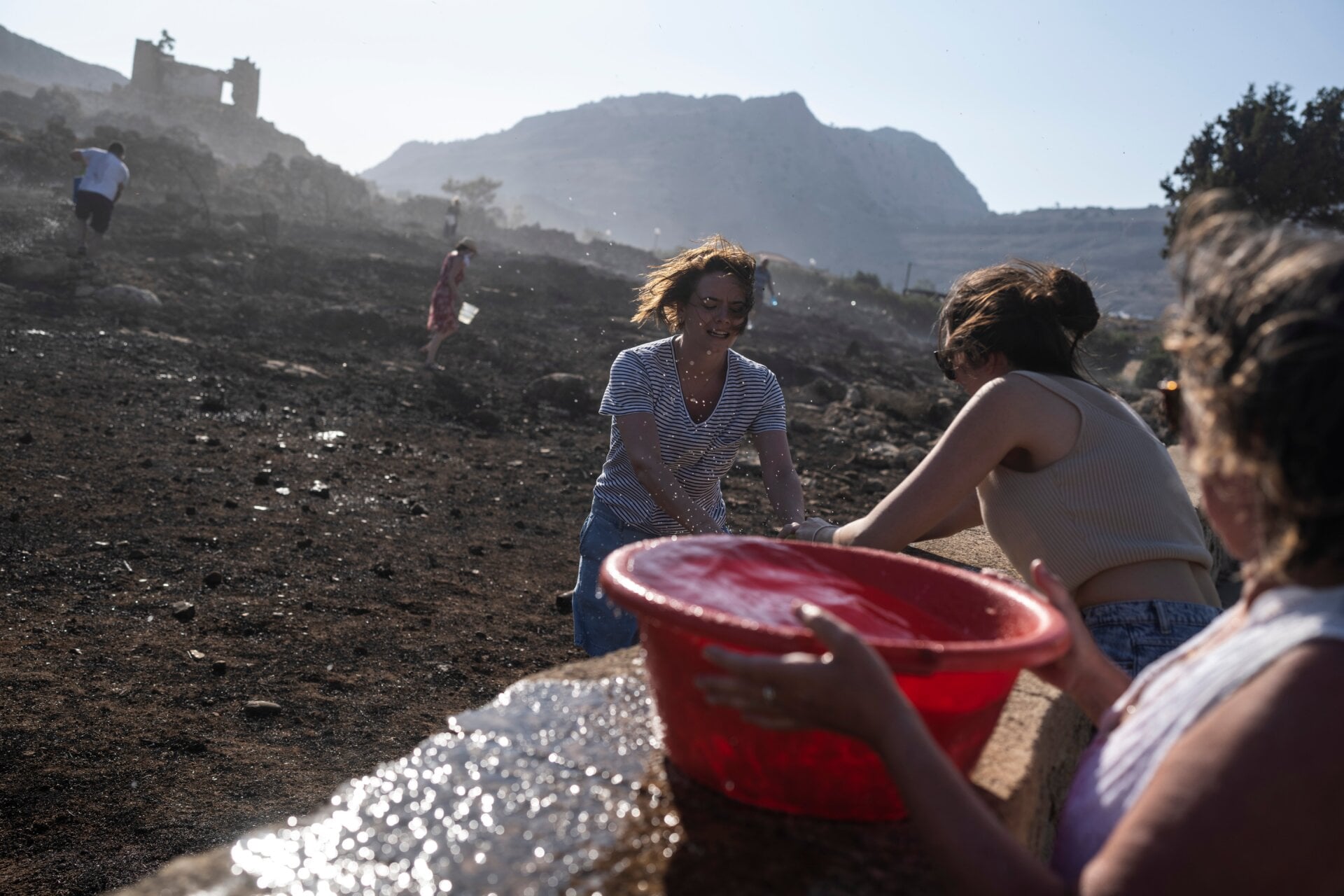 German tourists together with local residents try to extinguish a fire, near the seaside resort of Lindos, on the Aegean Sea island of Rhodes, southeastern Greece, on July 24, 2023.