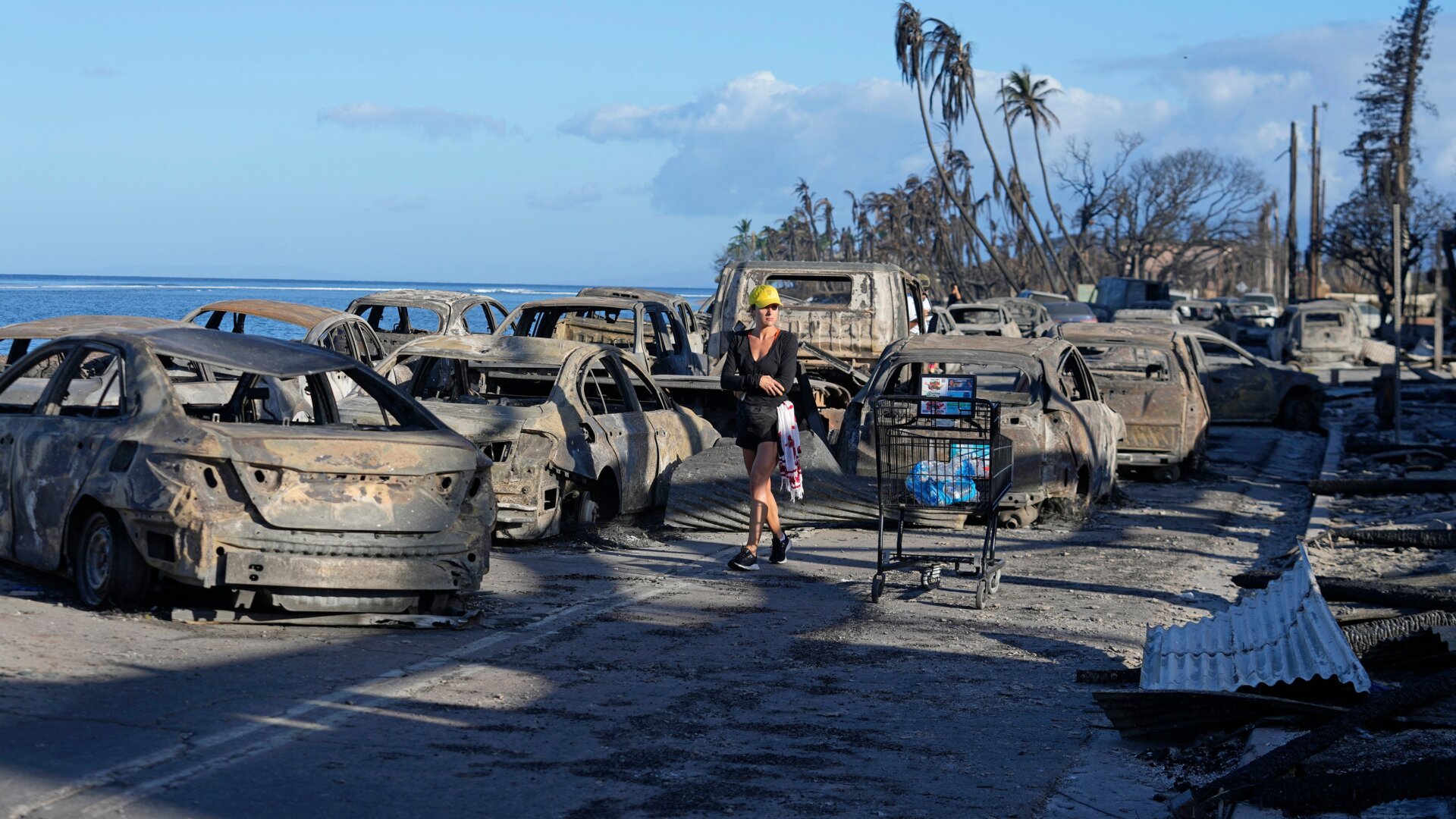 A woman walks through wildfire wreckage Friday, August. 11, 2023, in Lahaina, Hawaii.