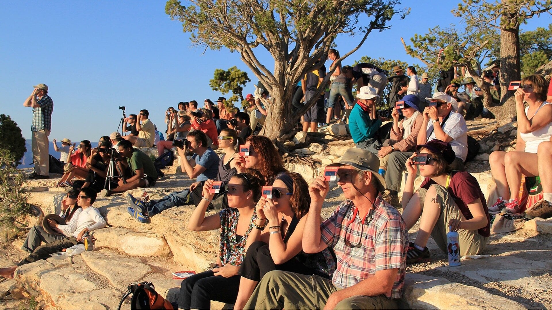 People using handheld solar viewers and solar eclipse glasses to safely view a solar eclipse.