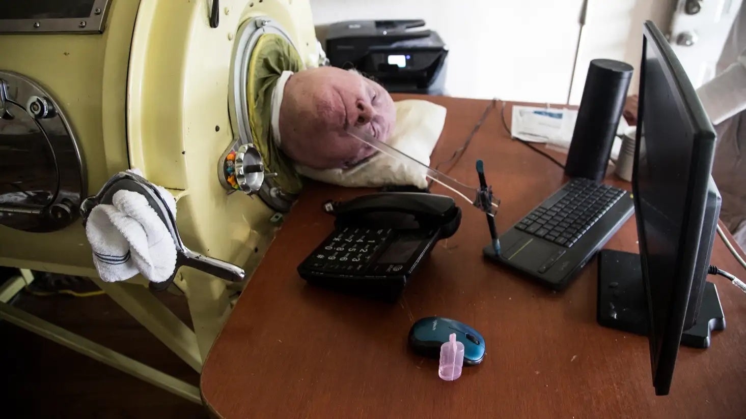 Paul Alexander writes his memoir using a pen attached to a stick.