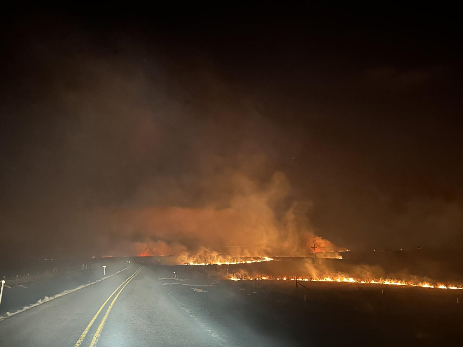   In this handout photo provided by the Texas A&M Forest Service,  fire crosses a road in the Smokehouse Creek fire on the evening of  February 27, 2024, in the Texas panhandle. 