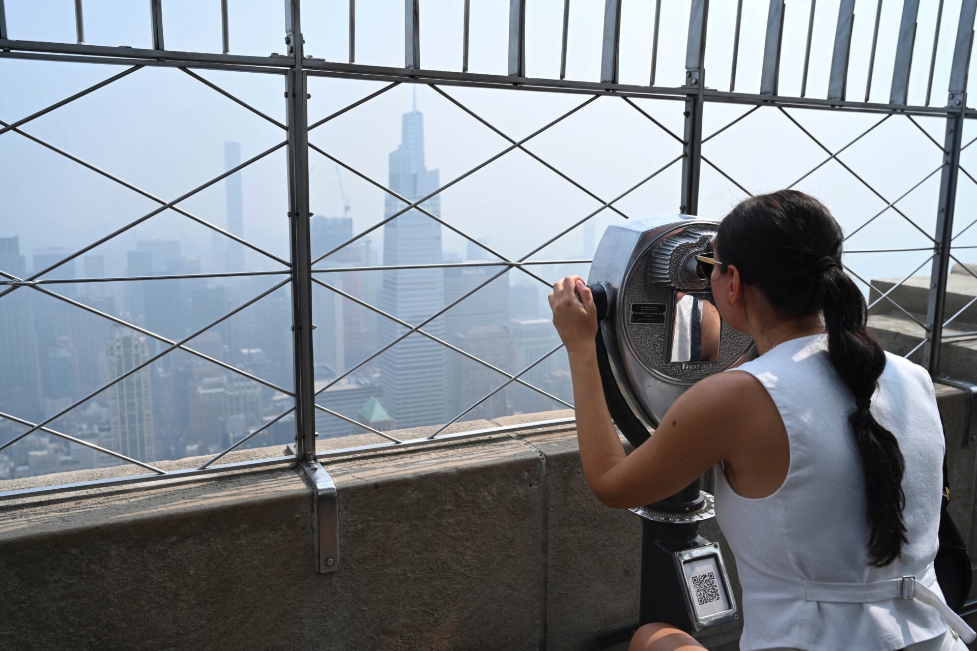 People visit the observation deck of the Empire State Building as smoke  from Canadian wildfires cover the Manhattan skyline on June 30, 2023 in  New York City.
