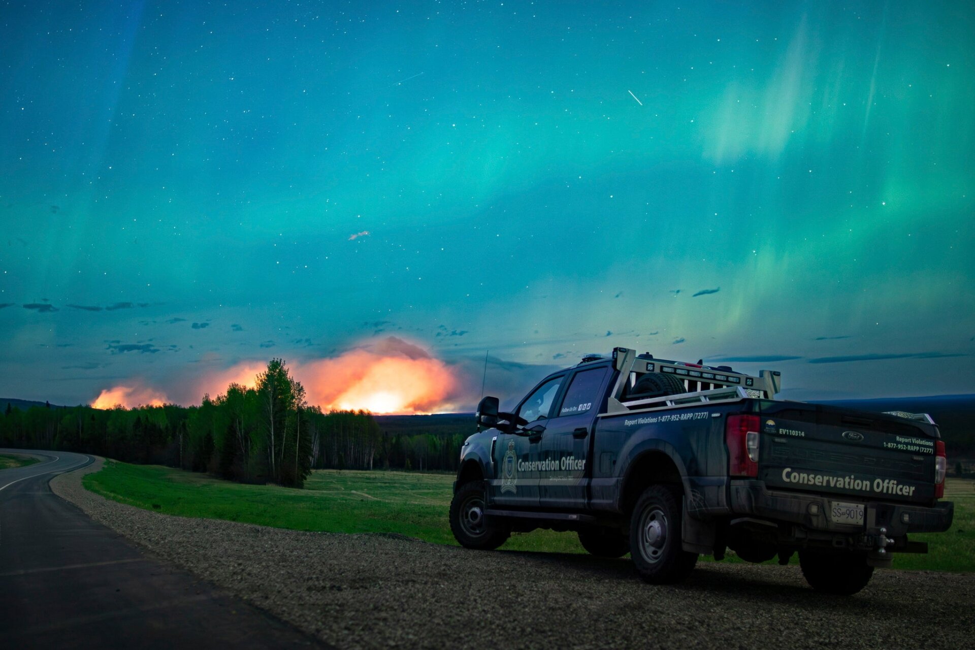 This photo provided by the Ministry of Water, Land and Resource  Stewardship shows a wildfire, Aurora Borealis overhead, near Fort  Nelson, British Columbia Saturday, May 11, 2024. 