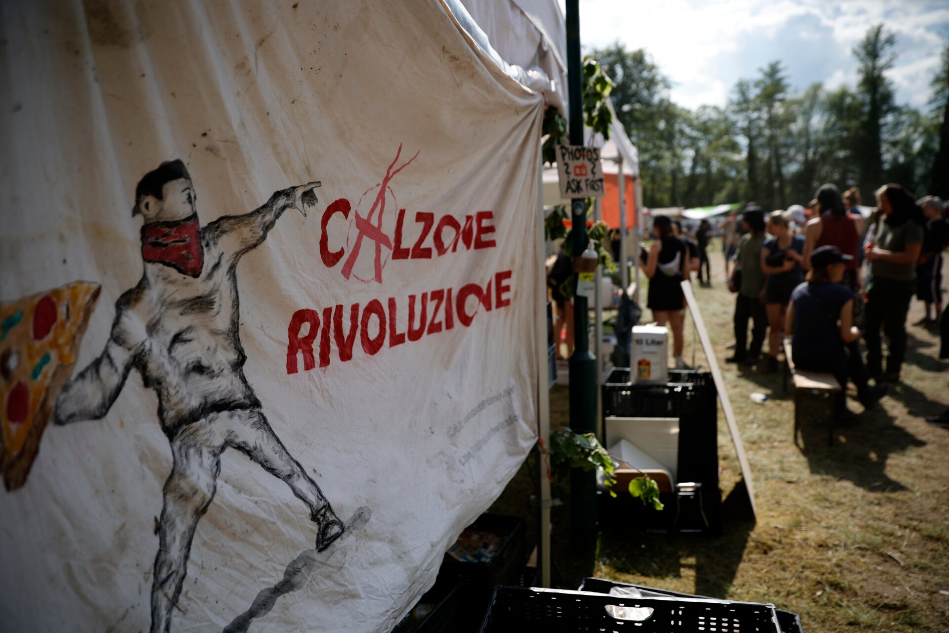 A picture of a militant activist throwing a pizza with the inscription “Calzone Rivoluzione” can be seen on a tent on May 10, 2024. 