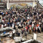 A large crowd of travelers waits to pass through security at an airport.