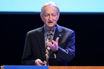 Geoffrey Hinton speaking at a podium.