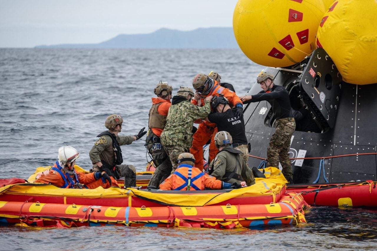 NASA astronaut and Artemis II pilot Victor Glover is assisted by U.S. Navy personnel as he exits a mockup of the Orion spacecraft in the Pacific Ocean during training Feb. 25, while his crewmates look on