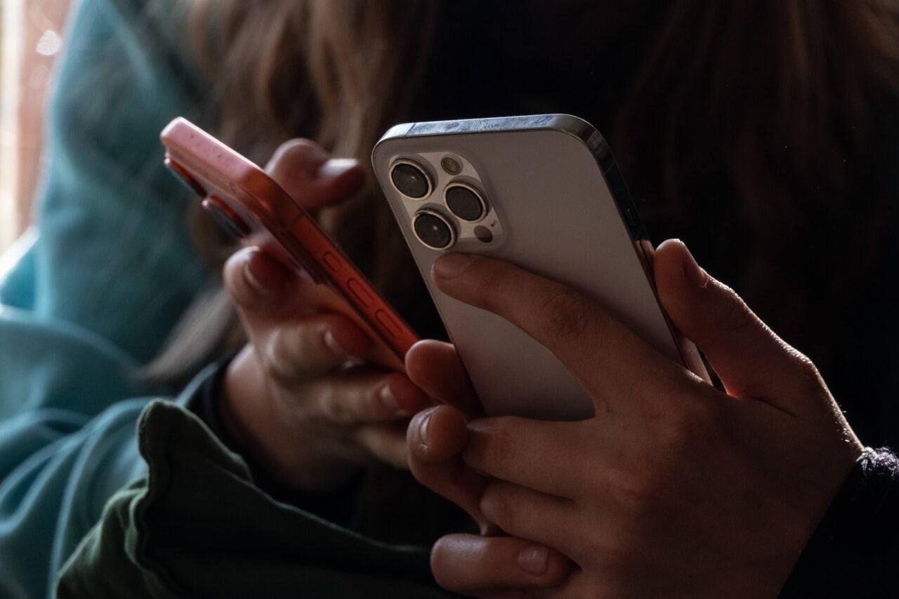 A photo of two teens holding their phones close together.