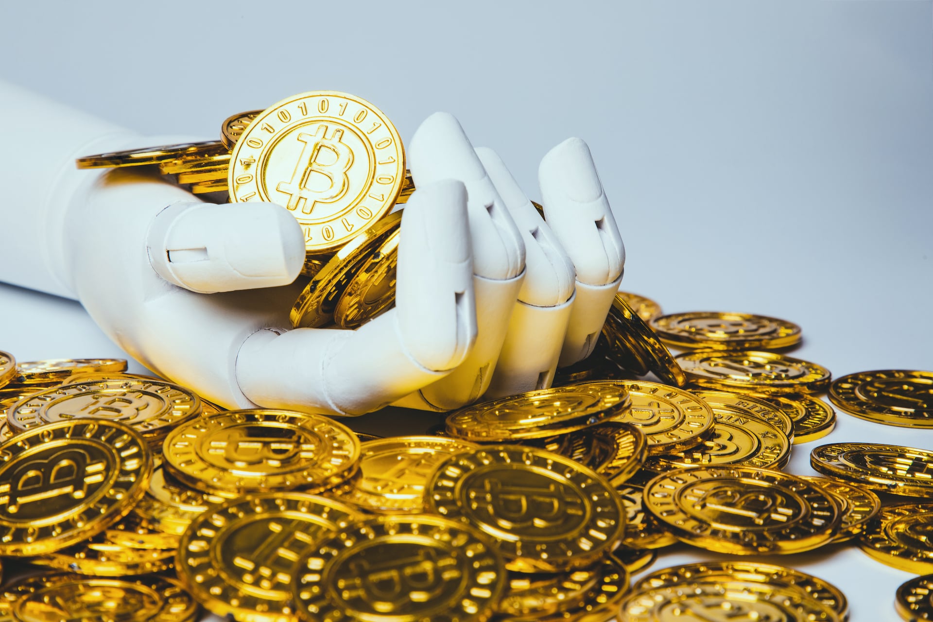 Stock photo of a robot hand holding prop bitcoins