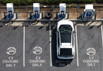 An electric vehicle charging at an electric vehicle charging spot, with nearby empty spots showing a sign that reads "EV CHARGING ONLY"