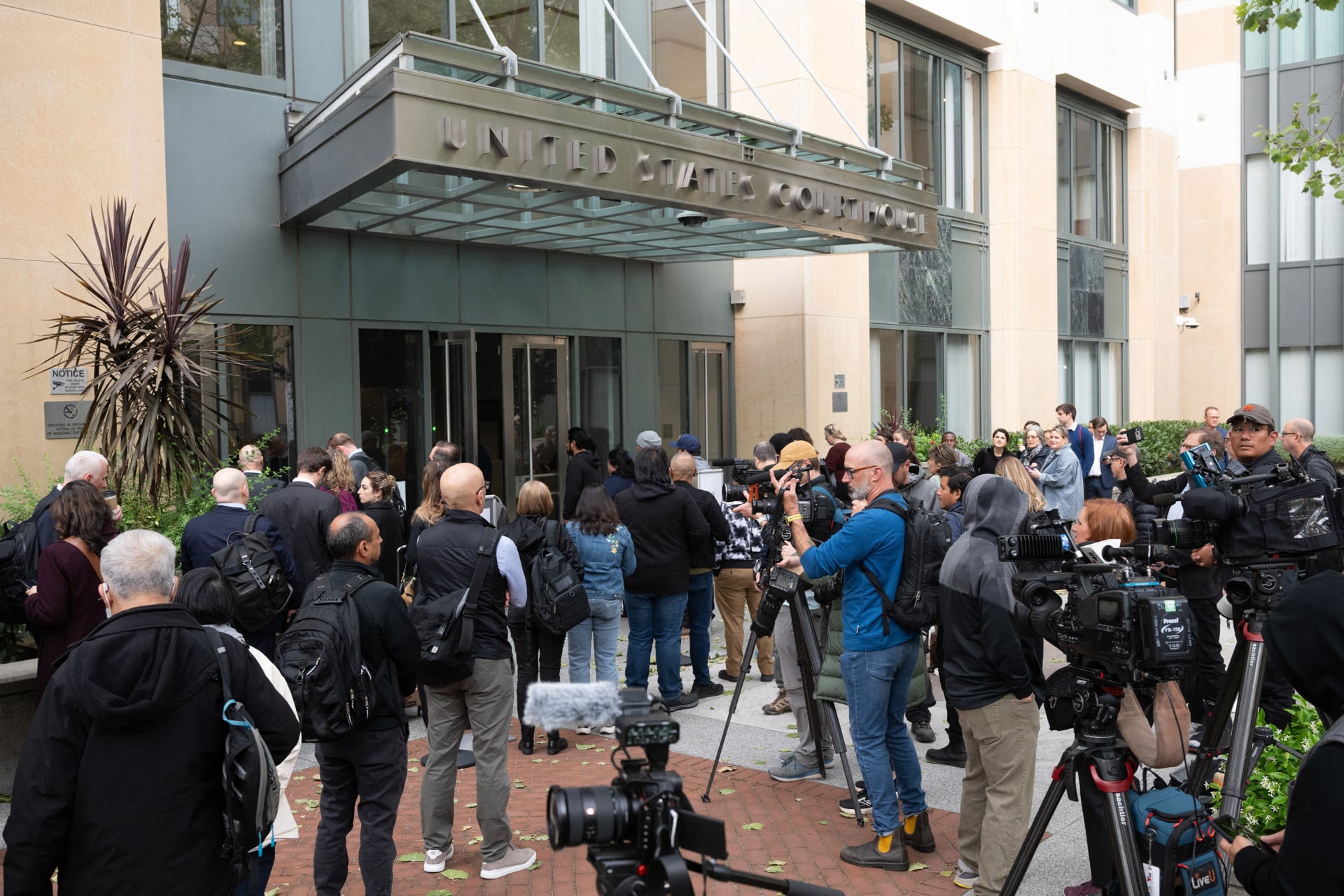 Attorneys and media cluster at the entrance of the Ronald V. Dellums U.S. Courthouse in Oakland, California, on April 27, 2026, for the start of the Elon Musk vs. OpenAI trial. 