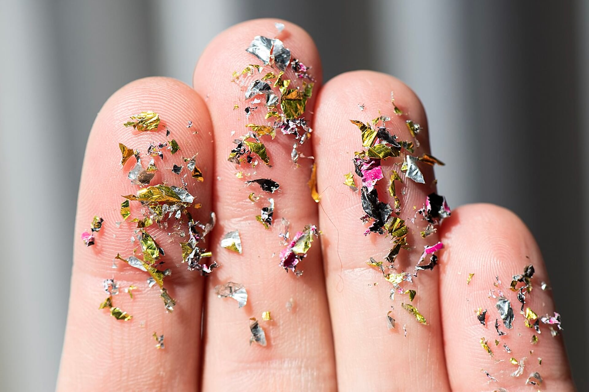 Above, some multicolored microplastics on the fingers of a human hand.