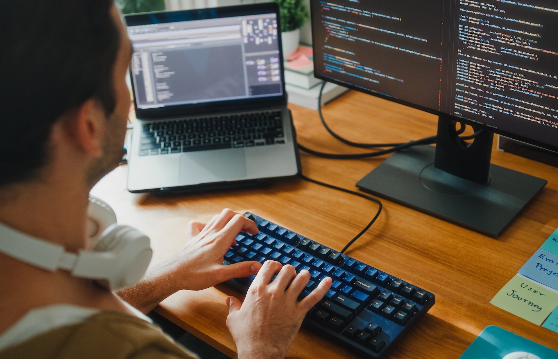 Closeup of young male computer programmer working on AI prompts web page designs coding user experience on laptop in bedroom at home.