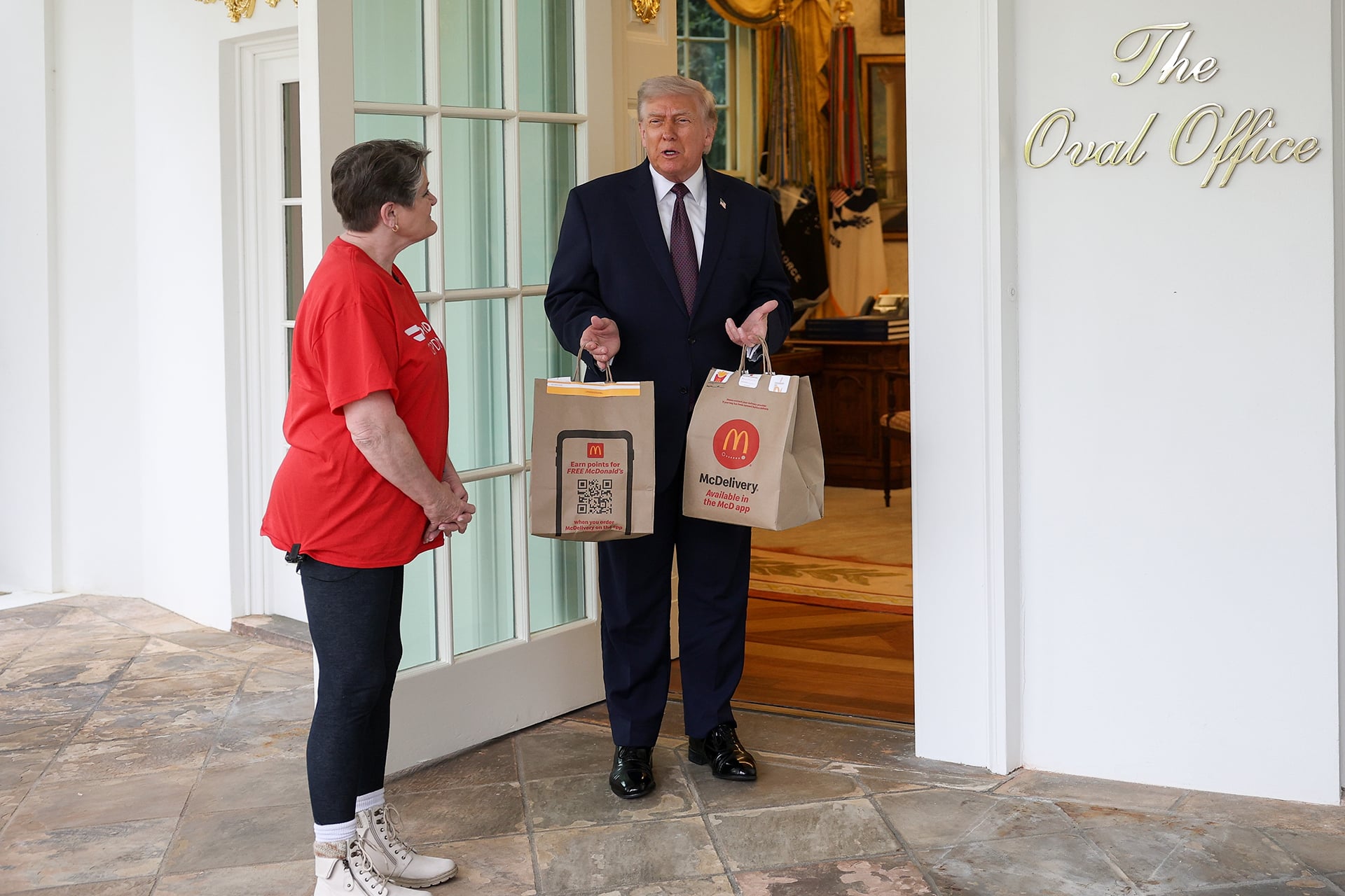 U.S. President Donald Trump receives a DoorDash delivery of McDonald's from Sharon Simmons before he speaks to the press during an event outside the Oval Office.