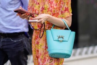 A woman uses her phone and an external phone charger while walking.