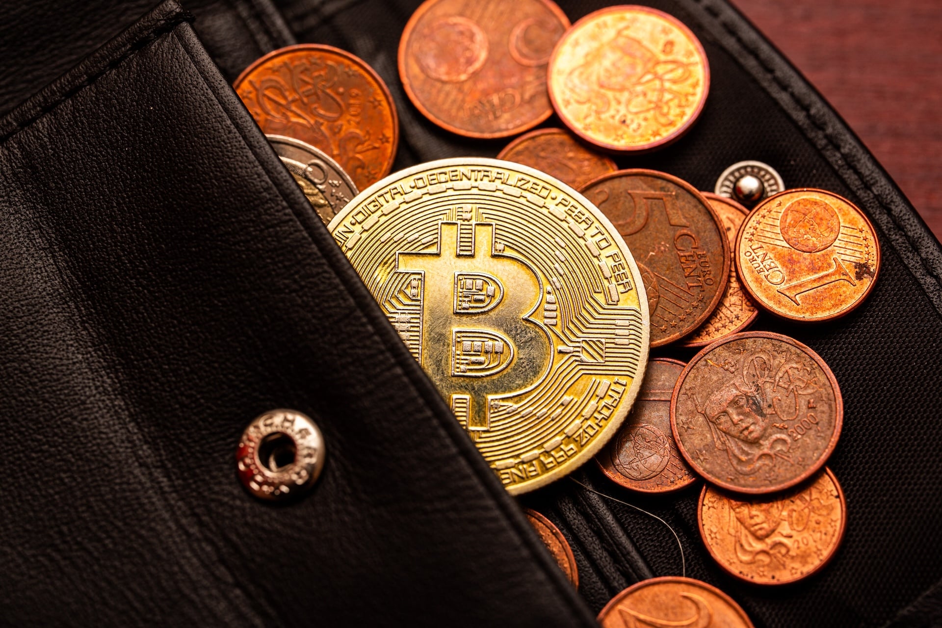 An image of a gold bitcoin coin in a traditional wallet.