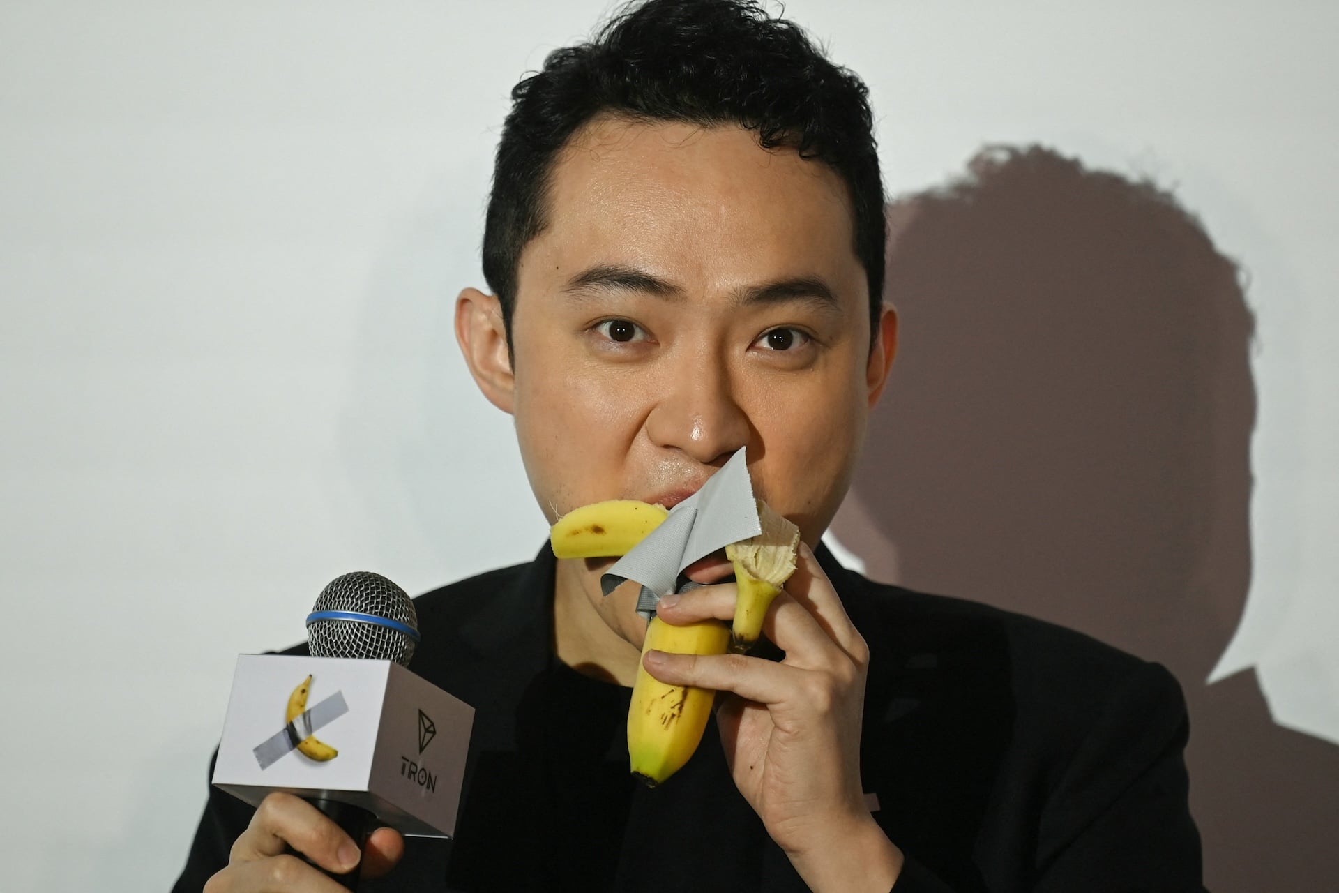 A photo of Justin Sun eating a banana at a press conference.