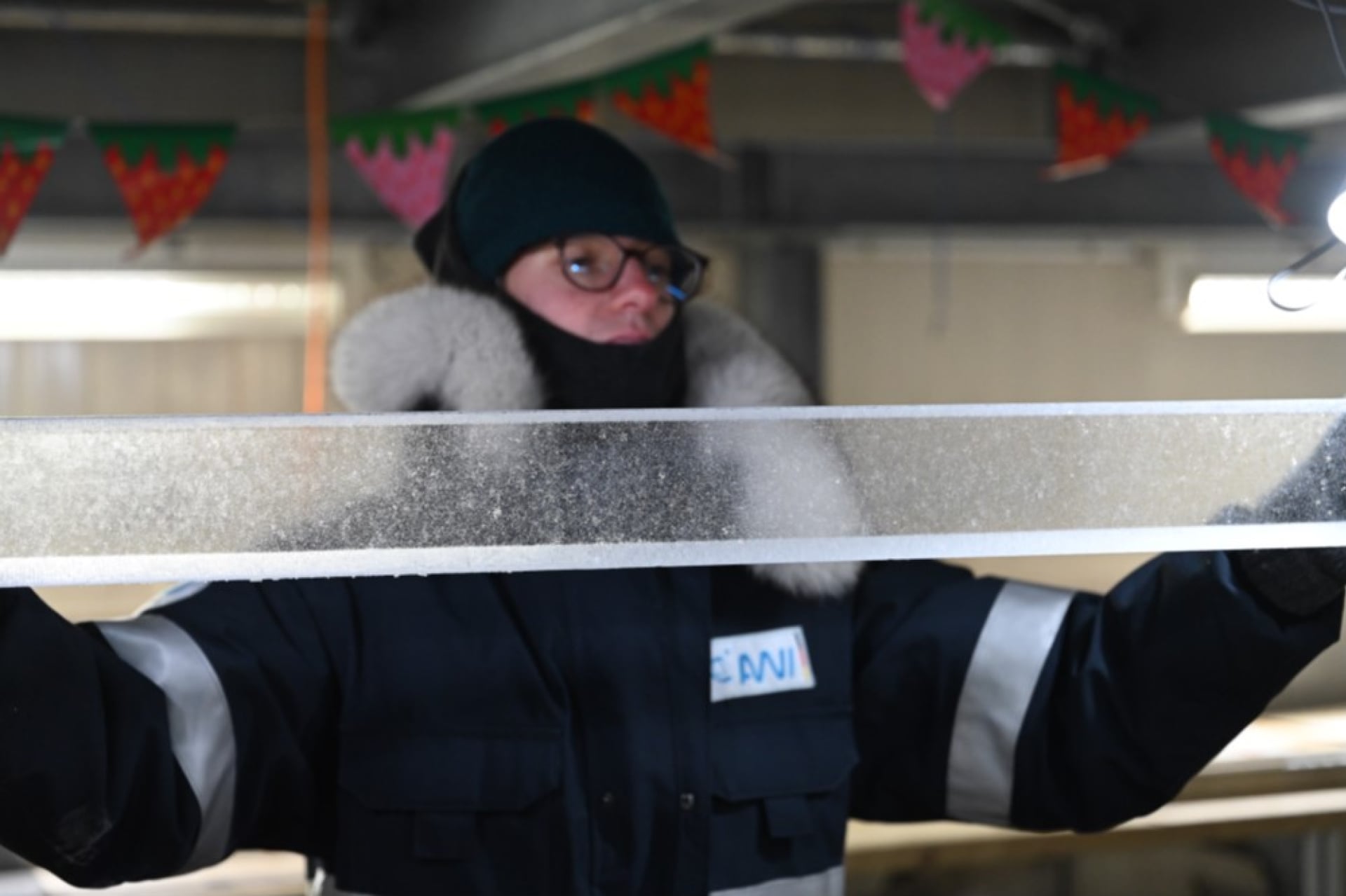 A researcher from the Beyond EPICA project holds up an ice core sample during the processing stage in 2025.