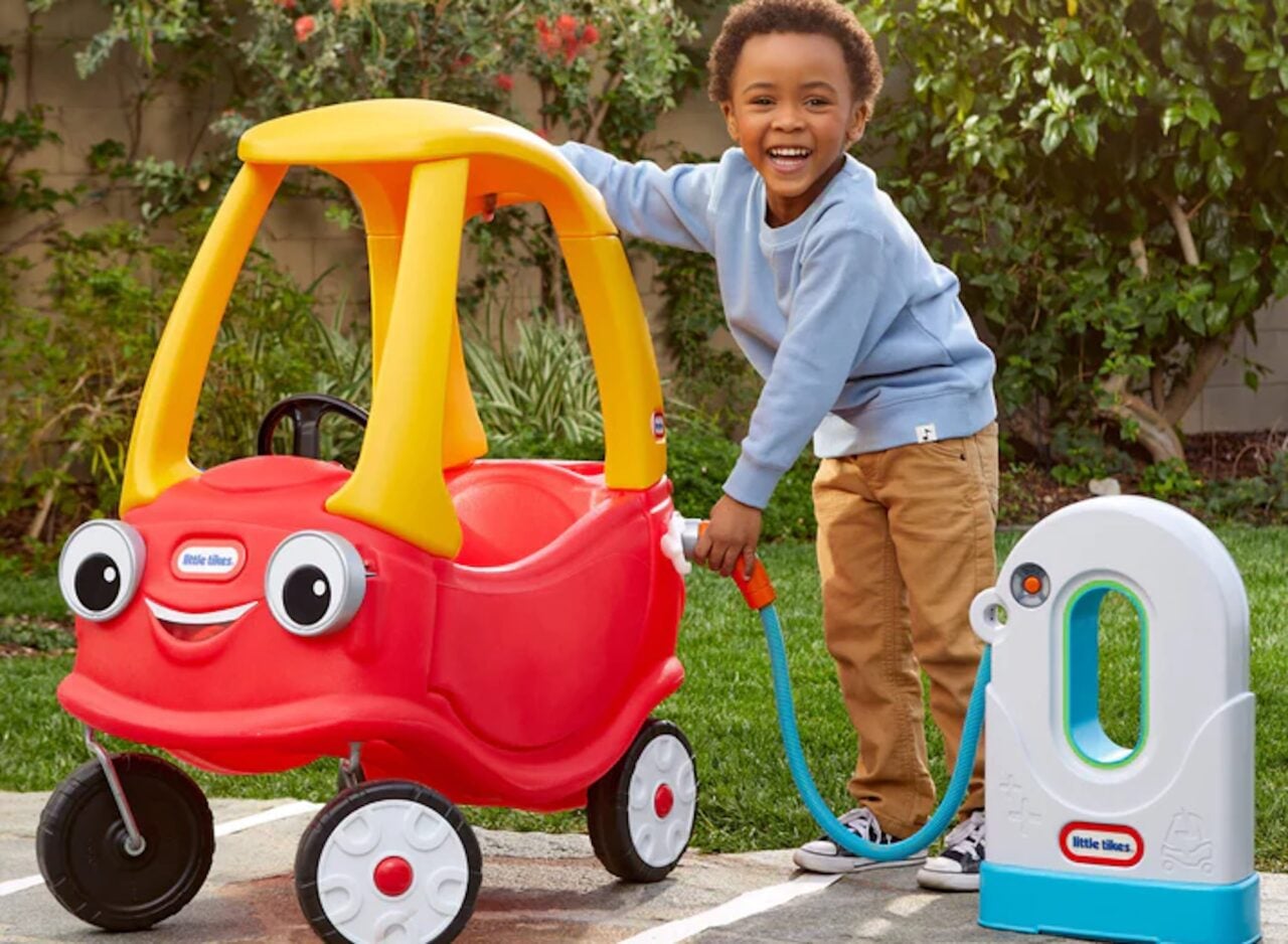 A small child pretending to use an EV charger on a ride-along toy car