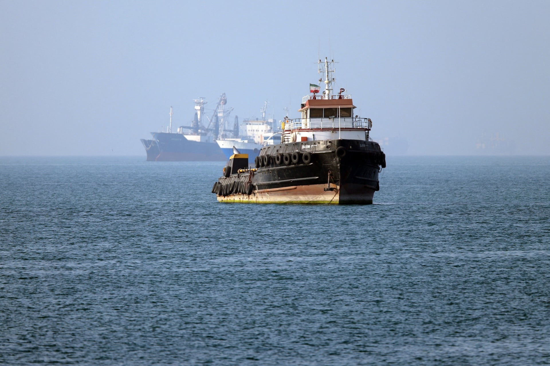 In this picture obtained from Iran's ISNA news agency on May 4, 2026, the Iran-flagged tugboat Basim sails near a ship anchored in the Strait of Hormuz off Bandar Abbas in southern Iran.